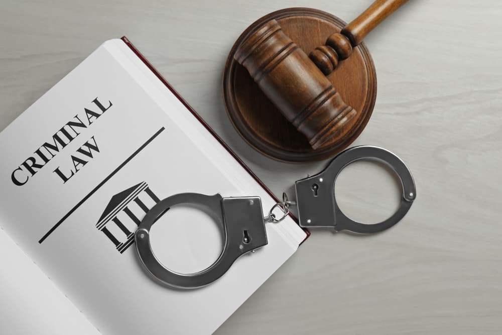 Judge's gavel, handcuffs and Criminal law book on white wooden background