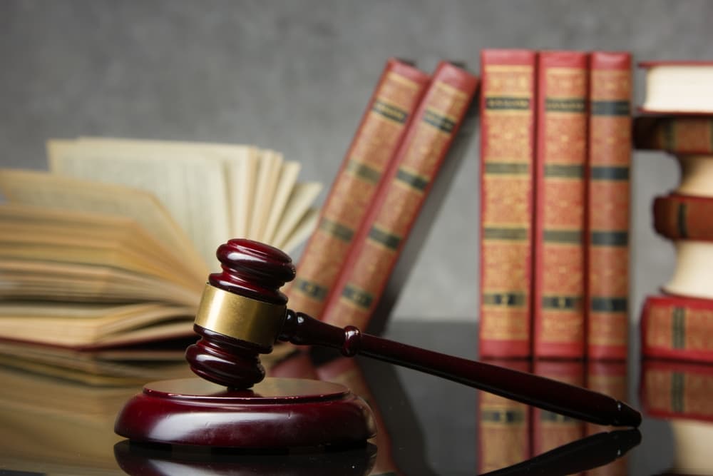 Open law book with a wooden judges gavel on table in a courtroom