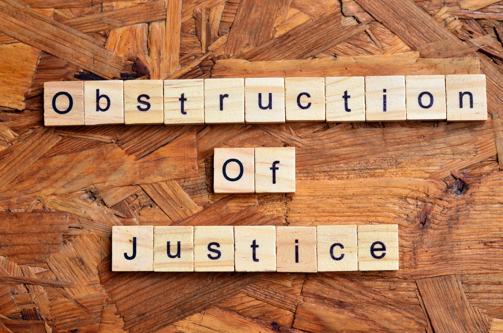 Wooden letter tiles arranged to spell 'Obstruction of Justice' on a wooden surface, symbolizing legal charges related to interfering with judicial proceedings.