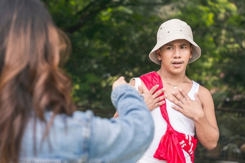 An individual pointing at a surprised man outdoors, highlighting a moment of confrontation or accusation in a public setting